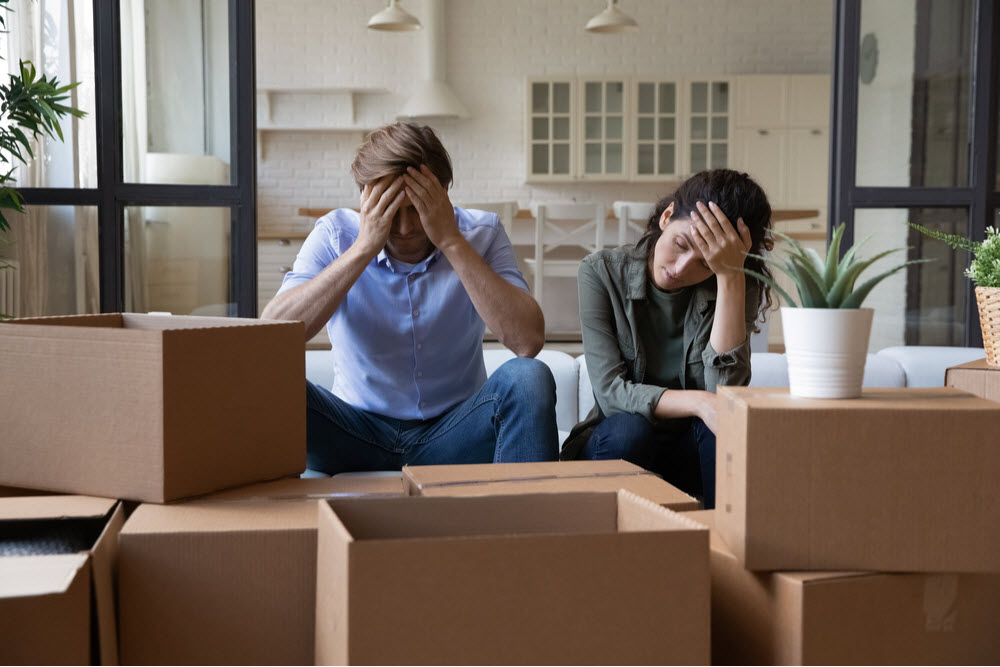 Exhausted couple sit rest on sofa in living room near cardboard boxes